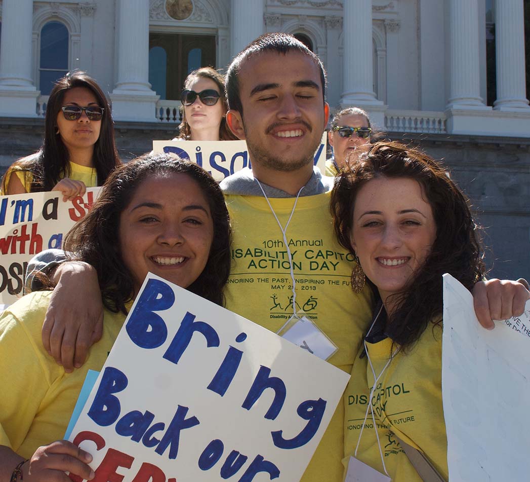 Photo of three friends together smiling at Disability Capitol Action Day (DCAD).