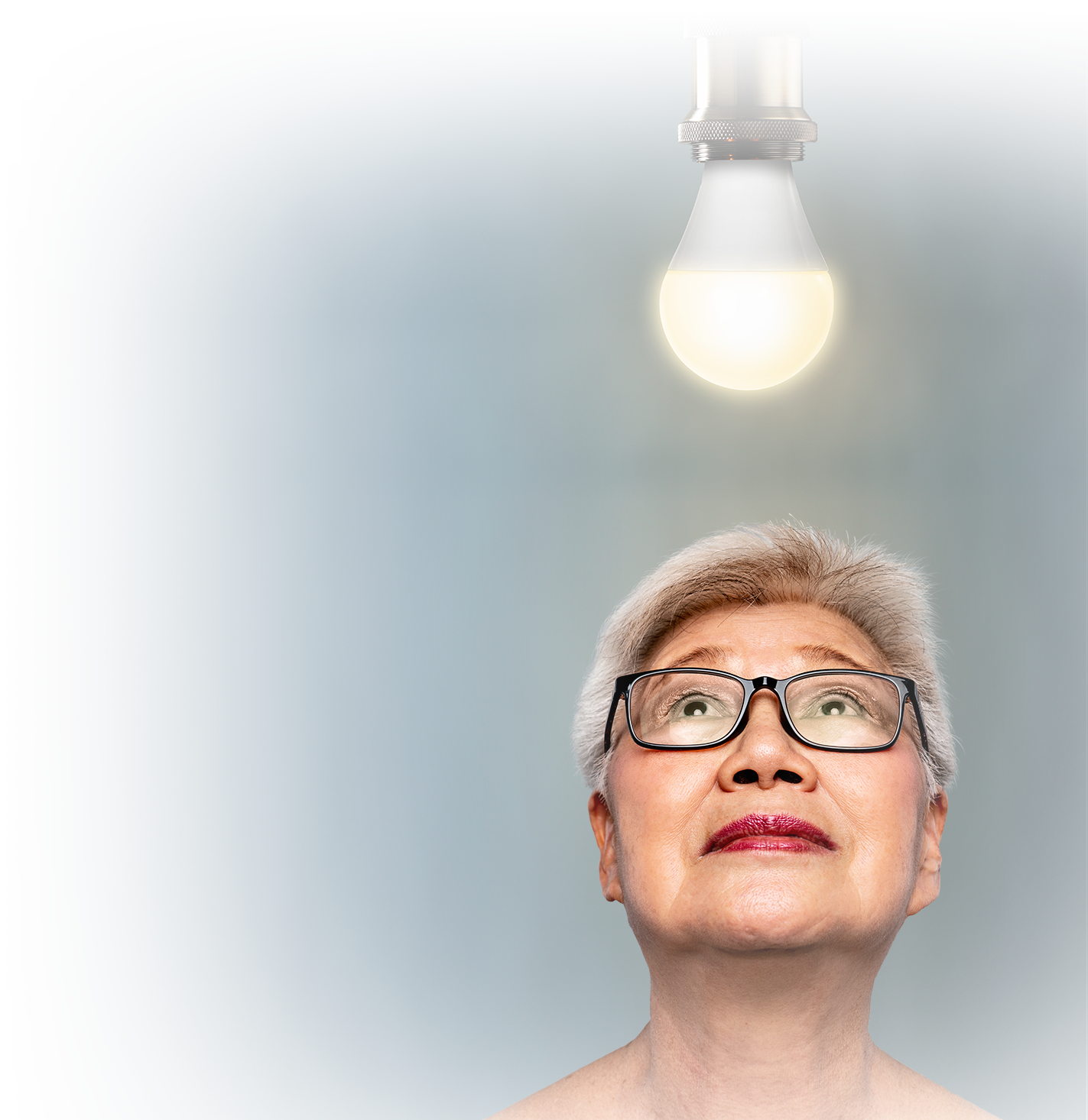 Photo of senior woman looking up at a light bulb. Photo of senior woman looking up at a light bulb.