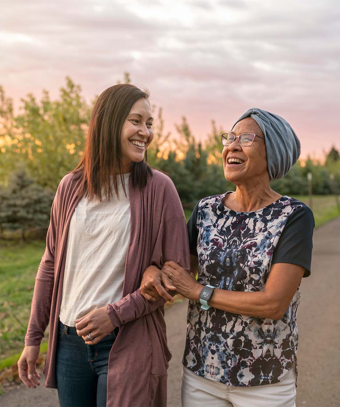Photo of older mother on an evening walk with her adult daughter, and both smiling.